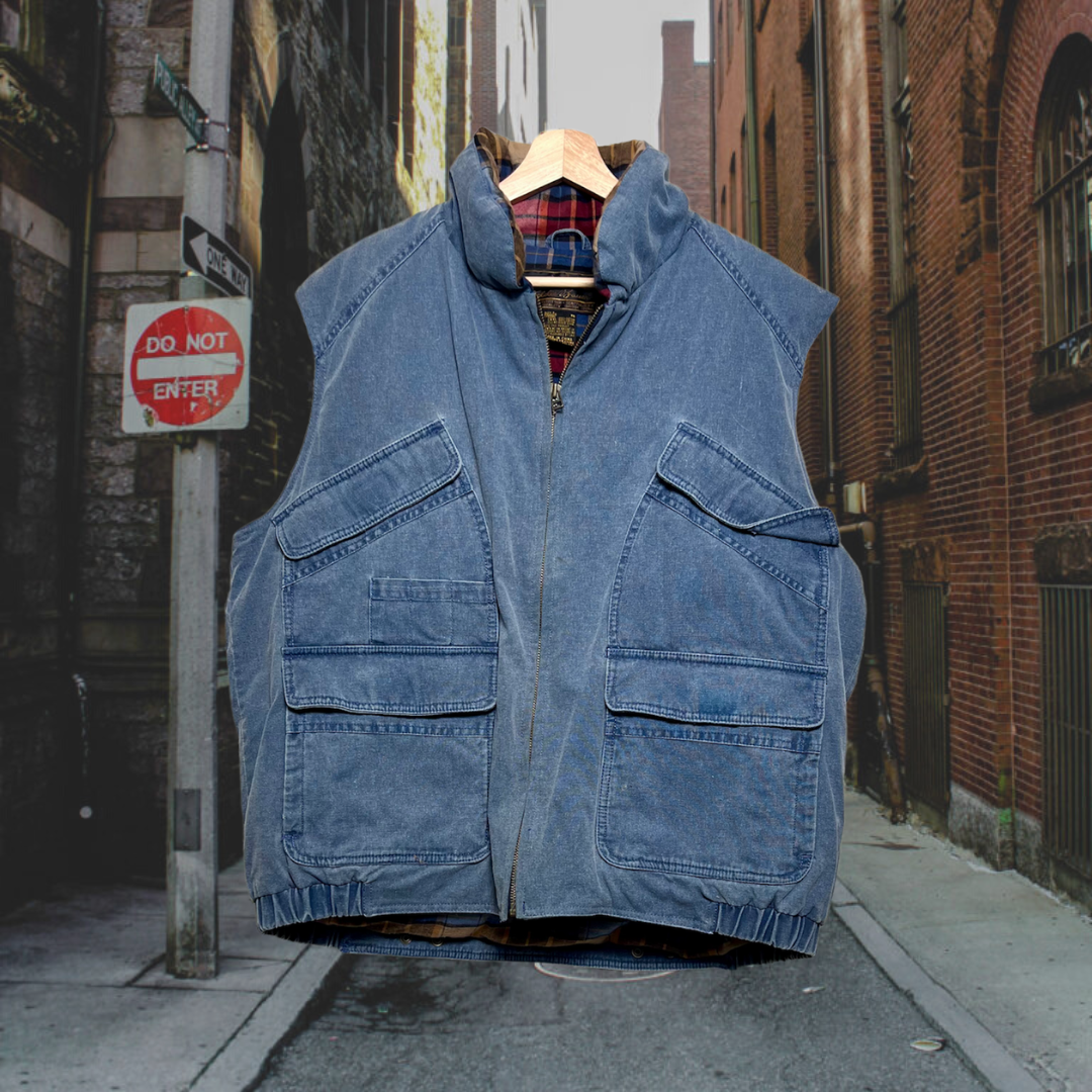 Front zipped vintage blue, zip-up, Eddie Bauer puffer vest w/ 2 chest pockets & 2 bottom pockets that fasten with Velcro. Lined with plaid cotton material. Good Kid Collective hand-picked this item.