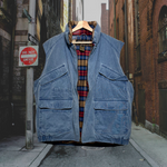 Load image into Gallery viewer, Front unzipped vintage blue, zip-up, Eddie Bauer puffer vest w/ 2 chest pockets &amp; 2 bottom pockets that fasten with Velcro. Lined with plaid cotton material. Good Kid Collective hand-picked this item.
