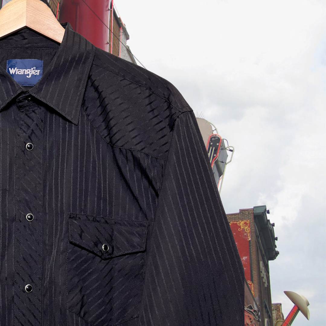Close-up of black, western Wrangler button-up shirt w/ black snap buttons and subtle black stripes. Good Kid Collective hand-picked this item.