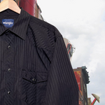 Load image into Gallery viewer, Close-up of black, western Wrangler button-up shirt w/ black snap buttons and subtle black stripes. Good Kid Collective hand-picked this item.
